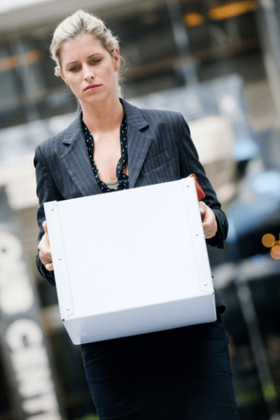 photo of a business woman carrying her office belonging in a box after being terminated