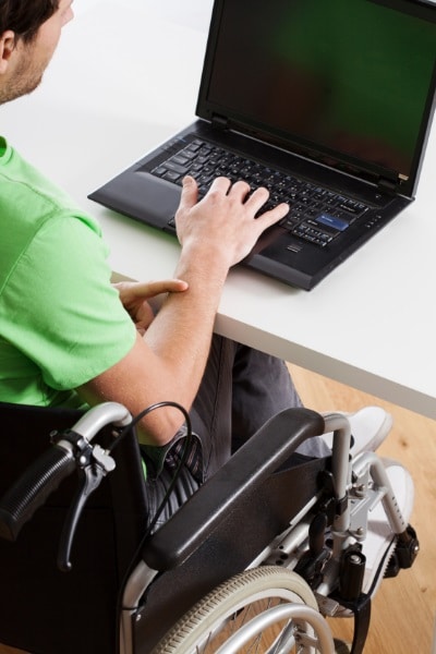 picture of a man with a disability in a wheelchair sitting at a desk