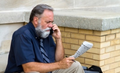 picture of an unemployed man look at the newspaper and talking on the phone